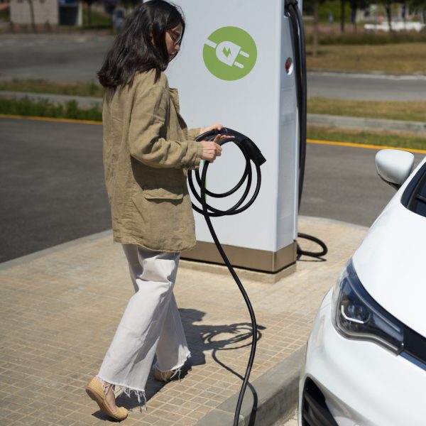 mujer-tiro-completo-cargando-auto-electrico_